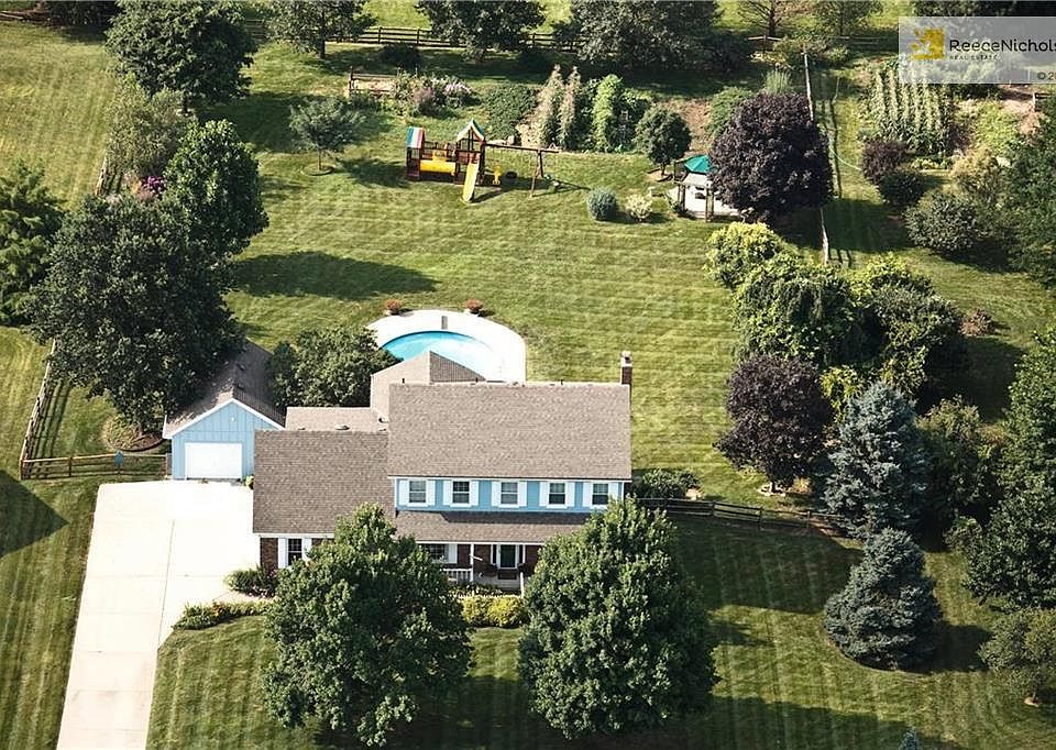 Aerial View of the Property situated on 1+/- acre lot with in-ground pool with diving board, slide, mature professional landscaping plus so much more!