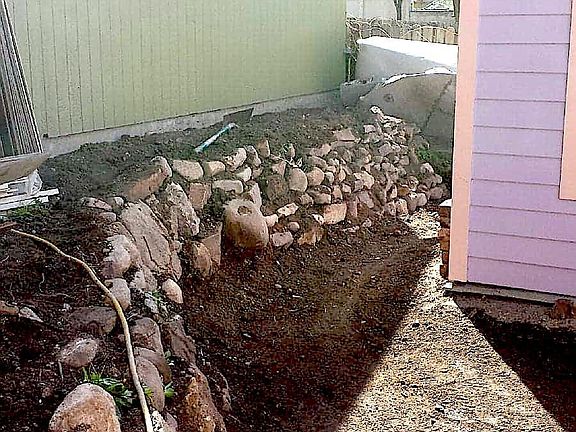 River rock retaining walls on east side of property. Raised area to left is small garden.