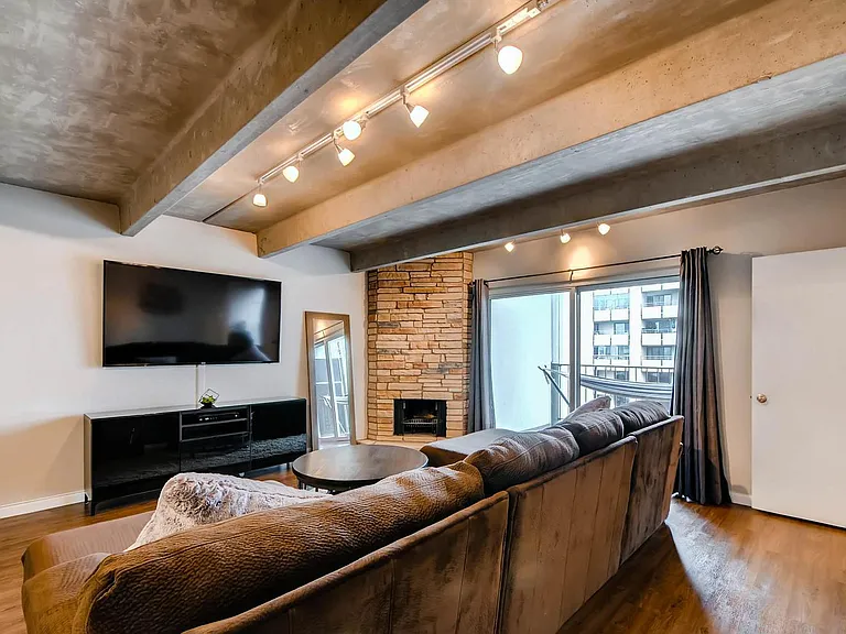 Living room with wood burning fireplace and balcony.
