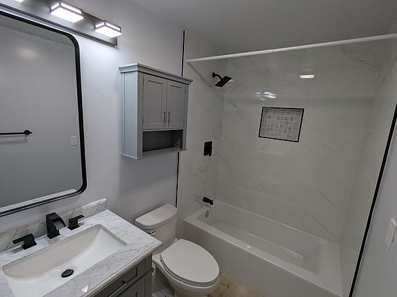 Marble tile wall, quartz vanity, new toilet.
