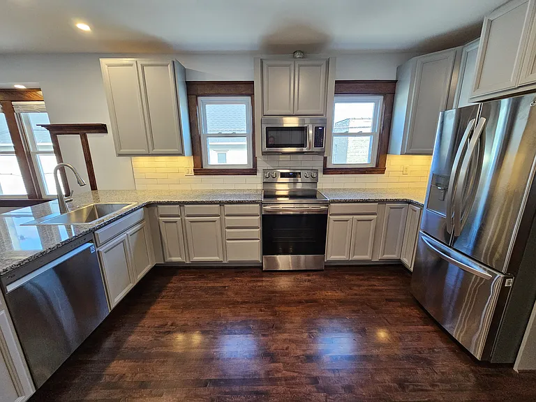 New kitchen cabinetry throughout, including cabinet with waste containers.