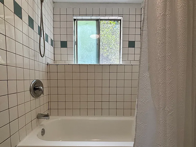 Large tub area with tiled ledge and window looking out at trees...