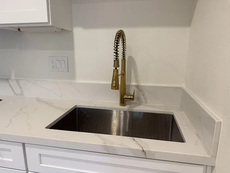 Premium KRAUS_ stainless steel sink, Kohler_ brushed gold faucet, and durable quartz countertops.