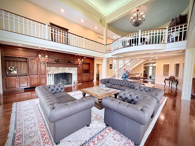View of the richly decorated great room with seating for up to seventeen, a massive stone fireplace, and a grand piano.