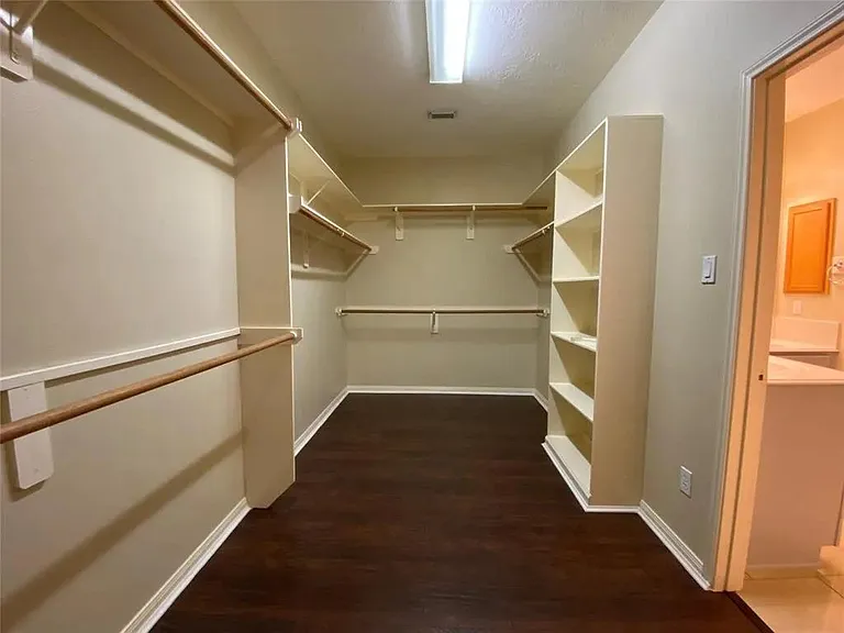Spacious walk-in closet with built-in shelving and multiple hanging rods for efficient wardrobe organization.