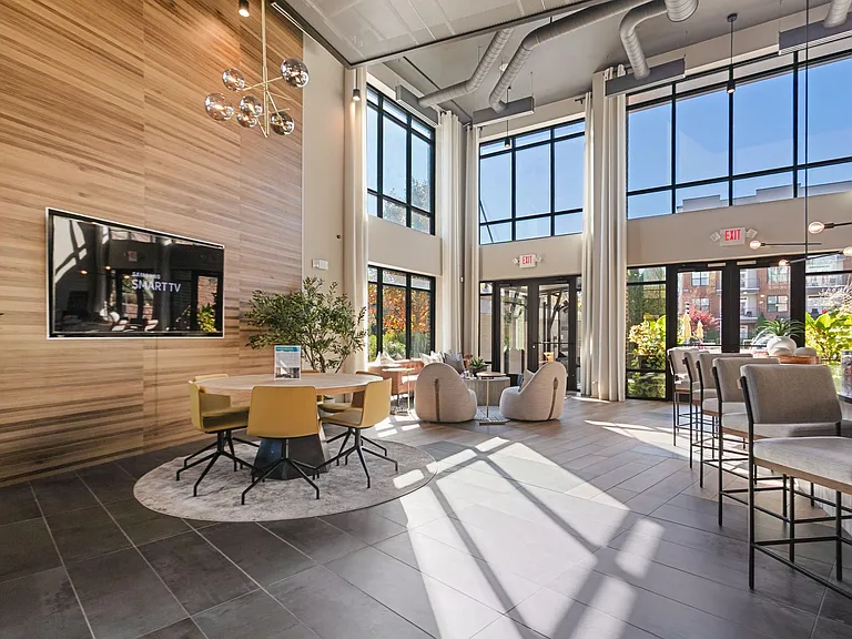 Sunlit clubroom with seating and courtyard views for a warm welcome home