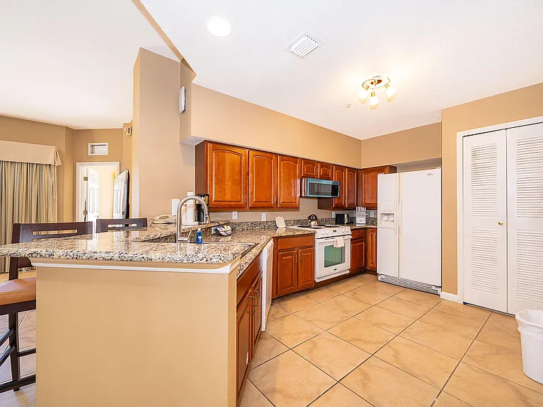 Kitchen features a granite breakfast bar, ample wood cabinetry, and a full appliance suite with generous prep space.