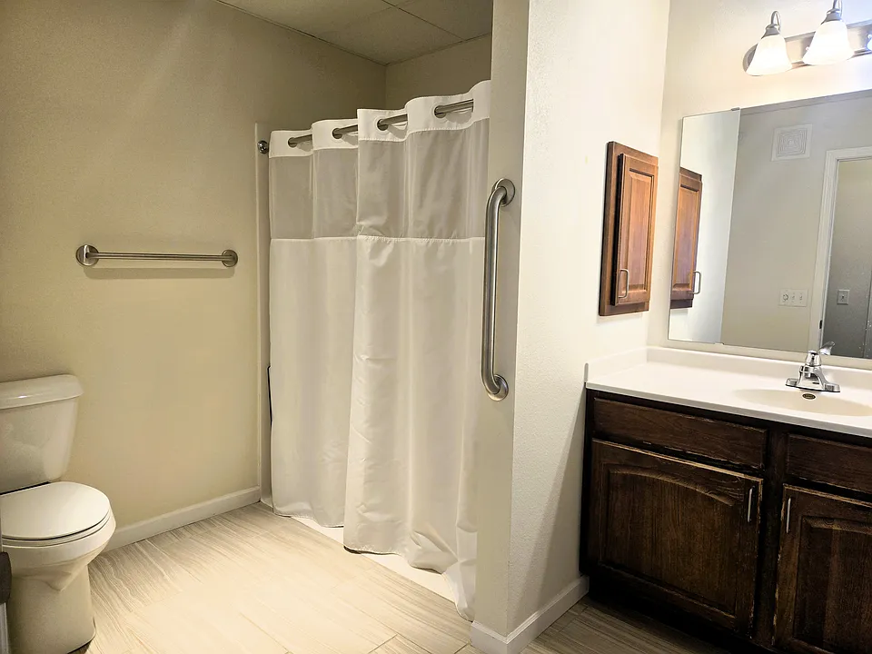 The bathroom features a walk-in shower with folding bench seat.
