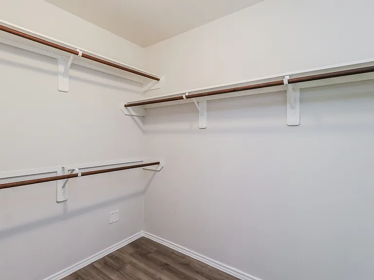 Spacious walk-in closet with elegant wood shelving and modern design, perfect for organized living. Spacious walk-in closet with elegant wood shelving and modern design, perfect for organized living.
