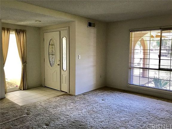 Front entrance into living room. Atrium is seen on left side of photo where homeowner can grow plants or remodel into an extra room. Atrium and front window allows loads of natural light!
