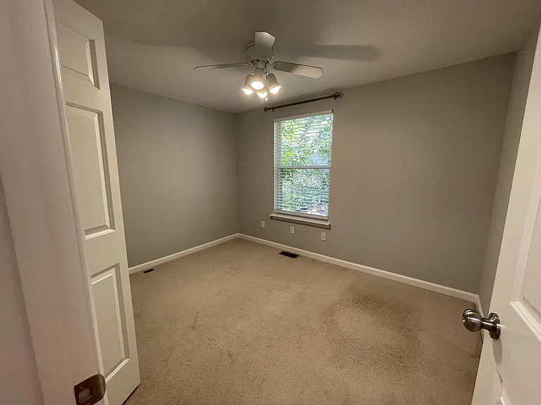 Second bedroom with ceiling fan, room darkening blinds, and curtain rod