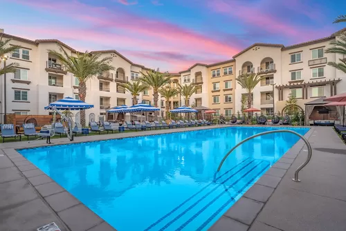 Resort-style pool with lounge seating and personal cabanas with TV's. - LIVIA at Scripps Ranch