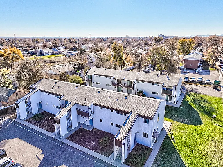 Aerial view of a charming residential complex surrounded by lush greenery and a tranquil neighborhood setting.