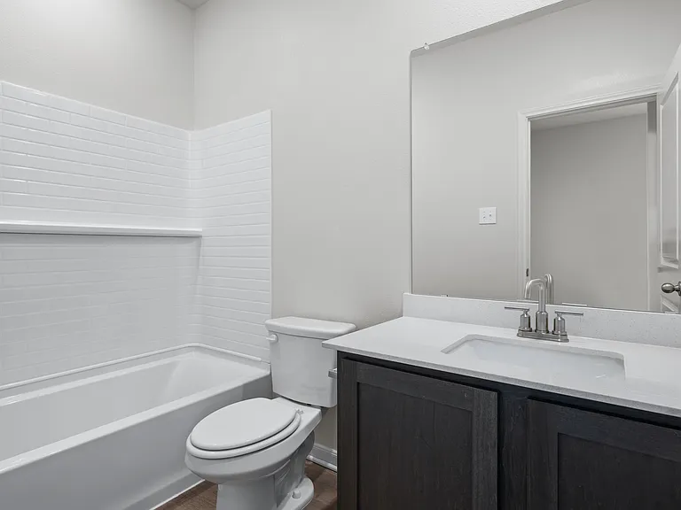 The secondary bathroom has a vanity and shower-tub combo.
