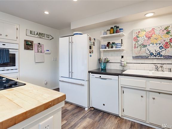 Bright white kitchen has wall oven and tiled backsplash