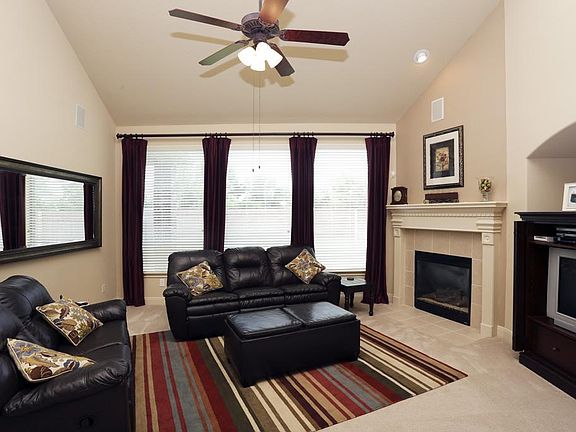 This family room that's designed for informal gatherings has a wall of windows and central fireplace.