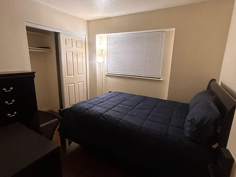 Furnished bedroom featuring a bed, dresser, and closet storage, plus a window with blinds for light and privacy.