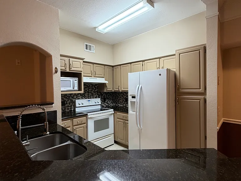 A fully equipped kitchen with a refrigerator, microwave, stove, and oven, ready for everyday cooking.