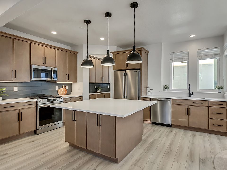 Modern kitchen with wooden cabinets, stainless steel appliances, and a white island under pendant li