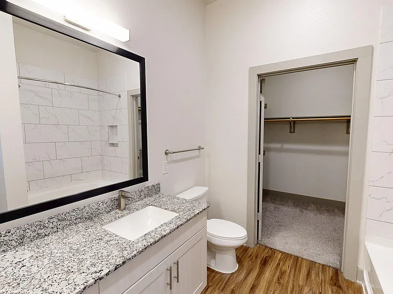 Apartment Bathroom with Wood Style Flooring and Spacious Closet.