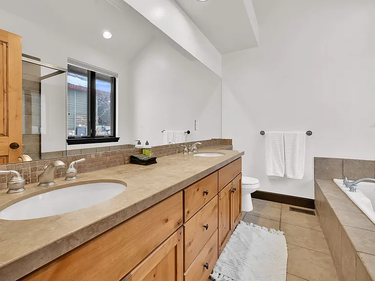 Master bathroom with his and hers sink, large tub, and walk in shower