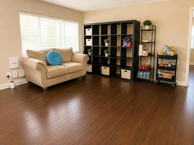 Spacious shared living area with hardwood floors, a comfortable sofa, large storage cubbies, and a convenient snack station.
