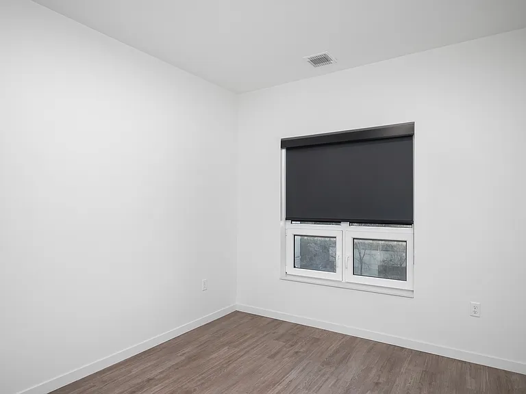 Chic and modern empty room with sleek flooring and a large window featuring a stylish black roller shade. Chic and modern empty room with sleek flooring and a large window featuring a stylish black roller shade.