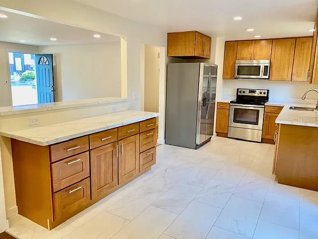 Remodeled kitchen with quartz countertops, stainless steel appliances and tile flooring