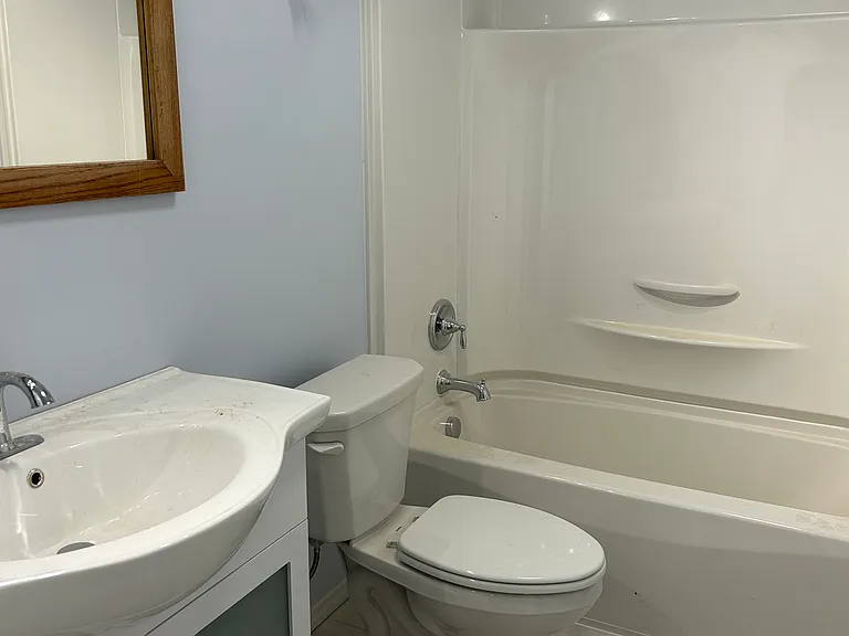 Bathroom: vanity, mirror, modern lightning, storage under sink, toilet, and shower/tub