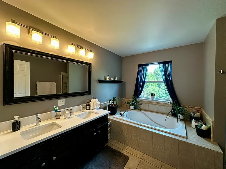 Primary bathroom with double sink, soaking tub, and shower stall.