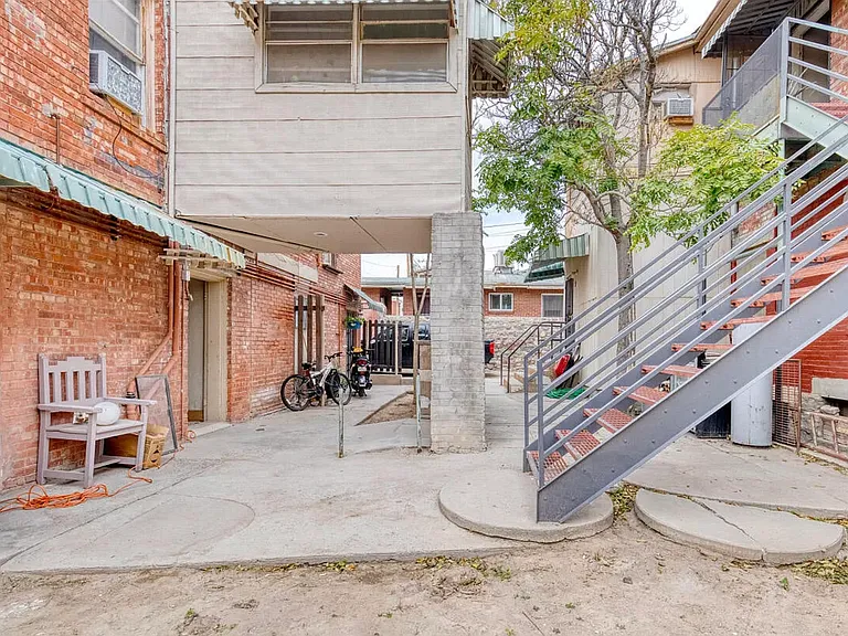 Photograph displaying front building (right) and back building (left). Apartment 5 is along the front building but access is through the back via the metal staircase