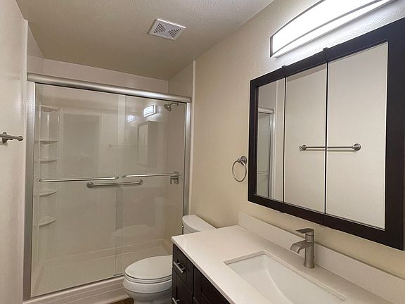 Bathroom with quartzite countertop, satin nickel fixtures and espresso colored cabinets and vinyl plank flooring.