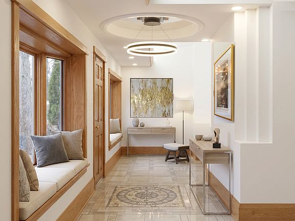 Bright main entrance hallway with a circular ceiling light, patterned tile floor, and a cozy window seating area.
