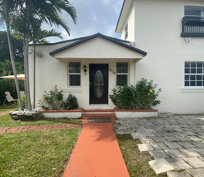 Front of the house. The house includes a garden on the left side of the house that is surrounded by hedges for privacy and shade. To the right of the house, there is a parking area on the property that you can see part of in the picture.