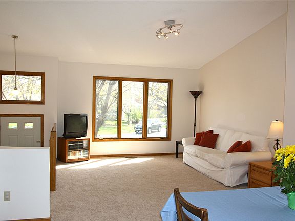 Living room w/ vaulted ceiling, large windows and a sliding glass door.