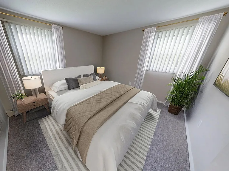 The Dickenson's bedroom showcases soft carpeting, neutral tones, and double windows that fill the space with natural light.