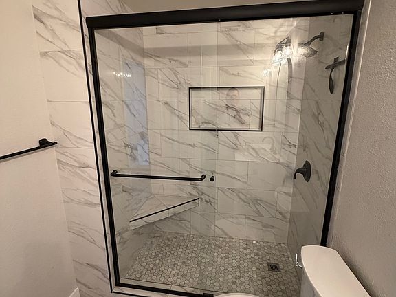 Remodeled guest bathroom with bench in shower