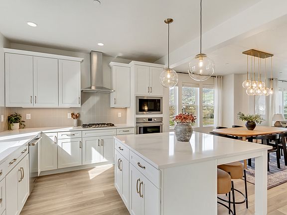 Modern kitchen with white cabinets, a central island with bar stools, pendant lights, and stainless