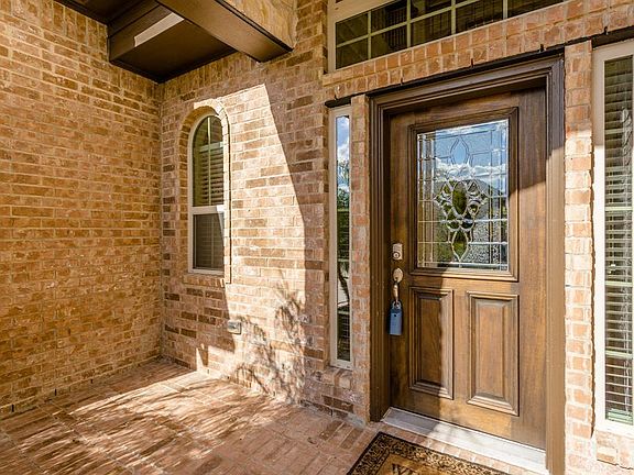 The two-story entry with brick porch and solid wood door with decorative leaded glass invites you in to this beautiful home.