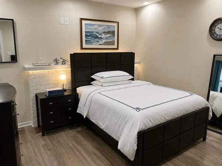 Well-appointed bedroom with a full bed, nightstand lighting, and durable flooring plus dresser and full-length mirrors.