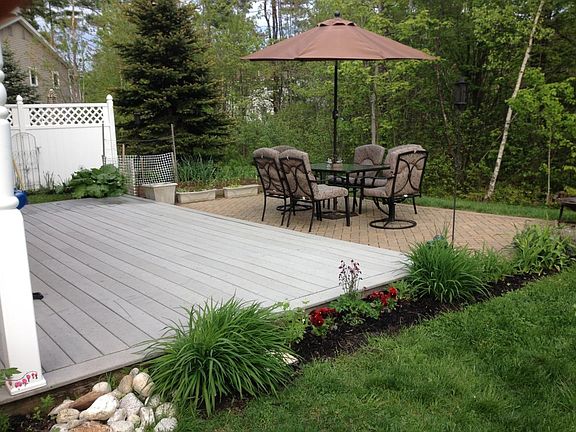 Deck and patio surrounded by gardens.