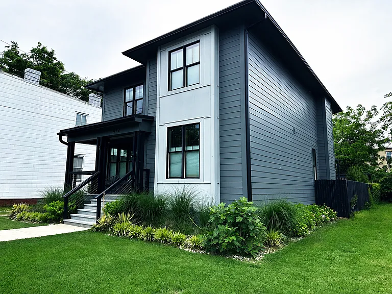 A grass access alley creates space between the house and neighboring houses.