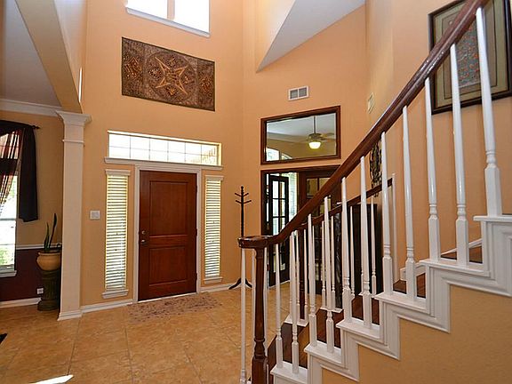 Enter into this elegant two-entry boasting soaring ceilings  and offering tile floors, double crown molding, and a gorgeous wood spiral staircase.