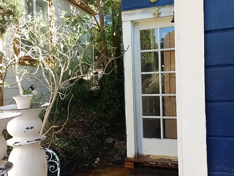 Front porch deck with another water view. Huge window under the lightly gilded look of the sconce, from the back bedroom with a private garden view.