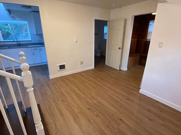 View of the main living area showing the kitchen to the left, full bathroom nearby, and enclosed porch access highlighting the flow and function to the space
