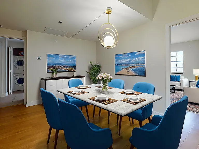 Elegant dining area with a marble table, surrounded by vibrant blue chairs, adjacent to a cozy living room with stylish decor.