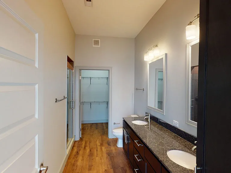 Apartment bathroom with wood-style flooring and double sinks.
