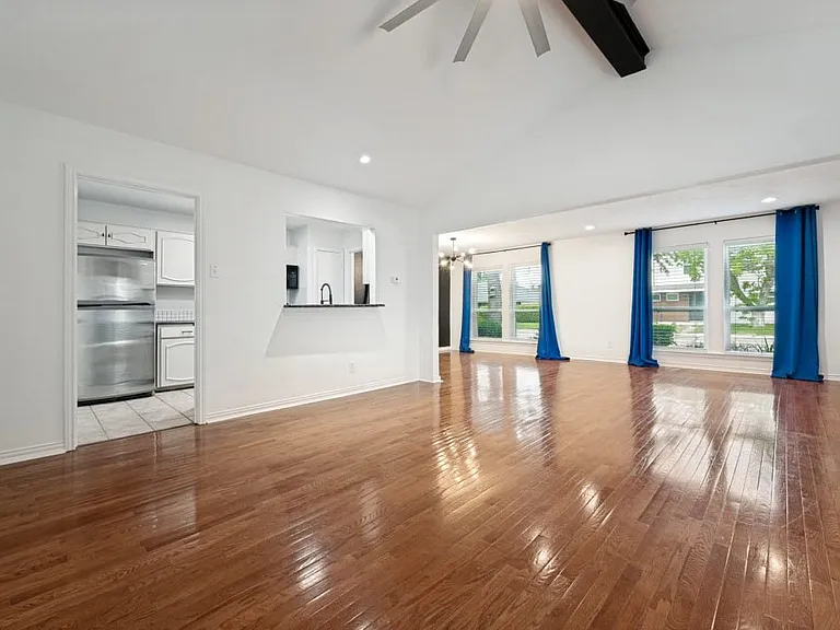 Spacious living area featuring polished wood-finish flooring, vaulted ceilings, and recessed lighting