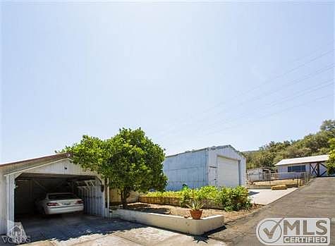 Multiple metal buildings.  Carport, 25'x40 pole barn with 13' clear ceiling, and 25 x 34 barn with two stalls and asphalt floor at the far right of the photo.