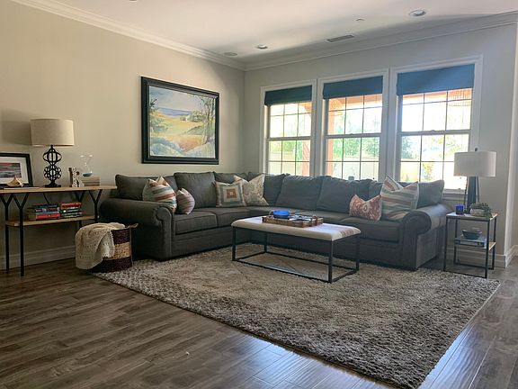 Family room with 65 inch HD TV, abundant natural light. Open floor plan with kitchen to the right.